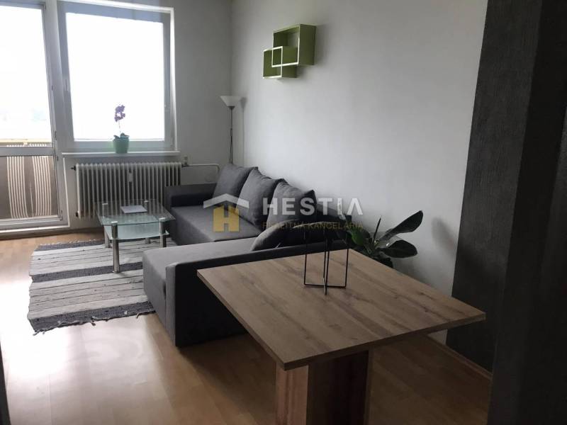 Nappali egy kétszobás lakásban kanapéval és fa dekorációjú padlóval.