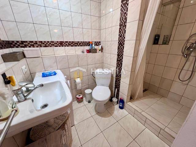 Fürdőszoba egy kétszobás lakásban WC-vel, zuhanyzóval és mosdóval.