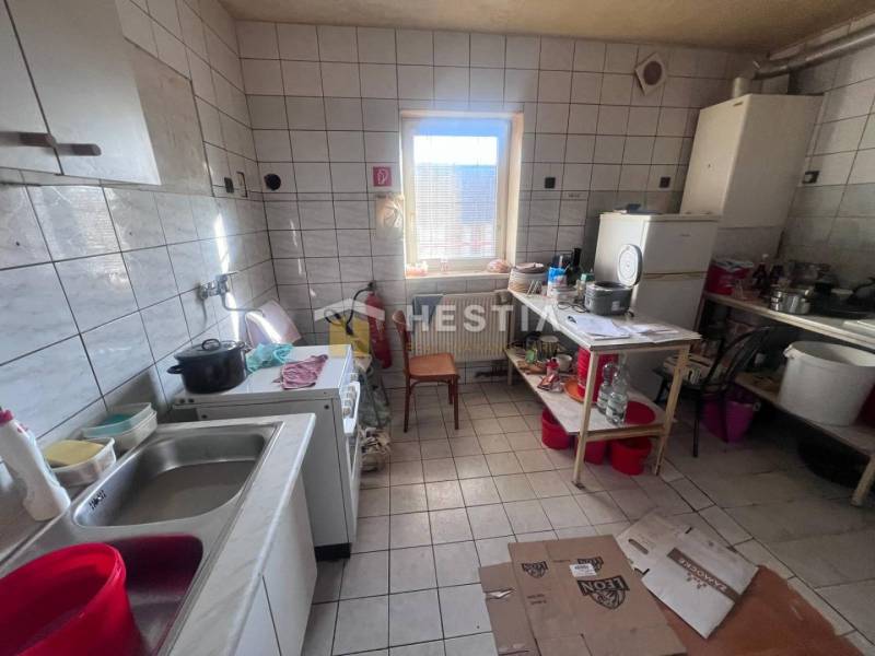 Konyha csempézett padlóval, tűzhellyel és polcon lévő edényekkel, vendéglátóipari helyiségek.