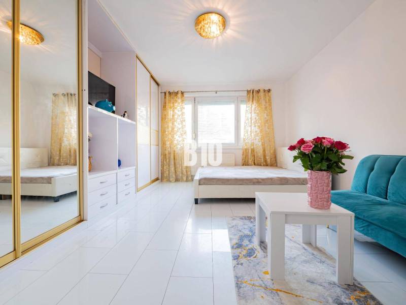 Nappali egy egyszobás lakásban tükörszekrénnyel és fehér padlóval.