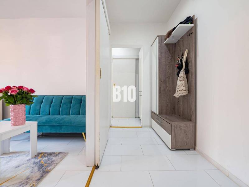 Hangulatos, egyszobás lakás világos belső térrel, kék kanapéval és fa bútorokkal.