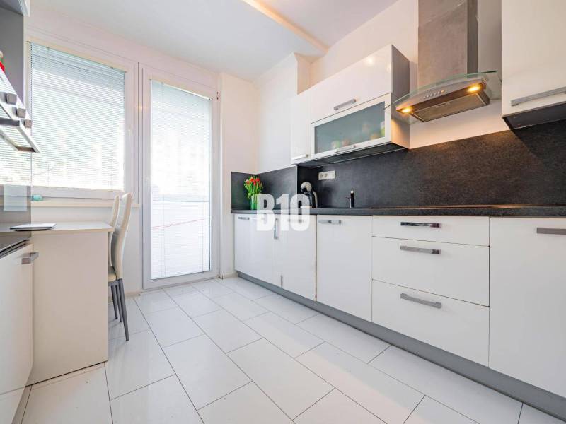 Konyha egy egyszobás lakásban fehér szekrényekkel és sötét munkalappal.