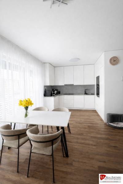 Étkezőasztal székekkel és konyha egy háromszobás lakásban, fa dekorációjú padlóval.