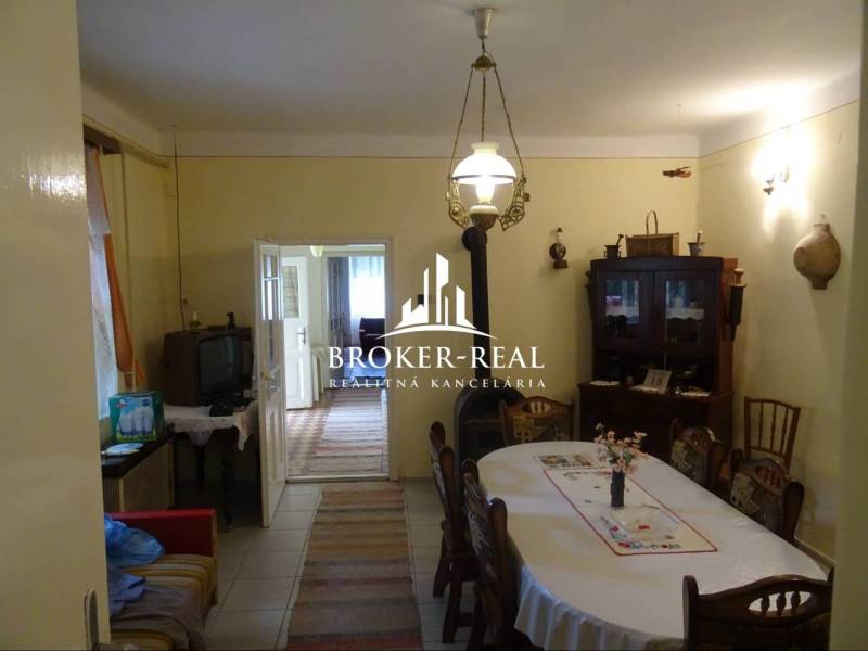 Ebédlő egy családi házban, fa bútorokkal, televízióval és bejárattal egy másik helyiségbe.