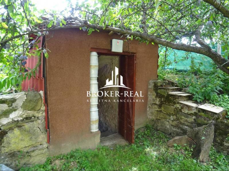 Kis kerti fészer a családi ház kertjében lévő kőfal mellett.