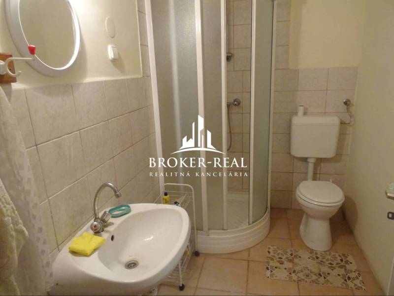 Fürdőszoba egy családi házban mosdóval, zuhanyzóval és WC-vel.