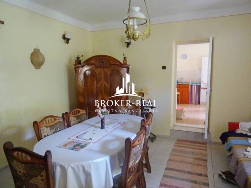 Ebédlő egy családi házban fa bútorokkal, asztallal, székekkel és mennyezeti lámpával.