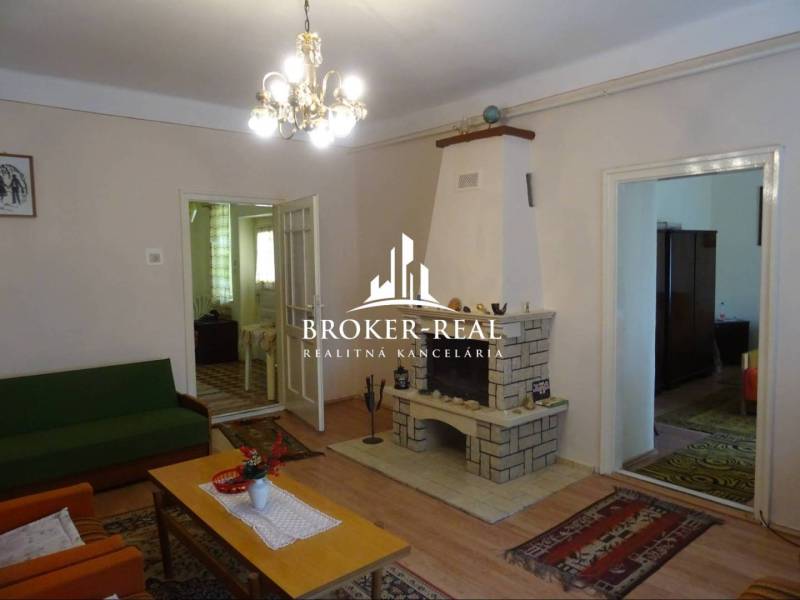 Nappali egy családi házban kandallóval, fa hatású padlóval és csillárral.