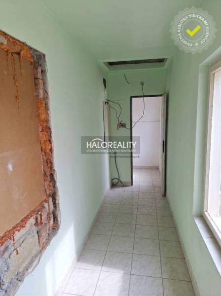 Keskeny belső tér világoszöld falakkal és csempézett padlóval.