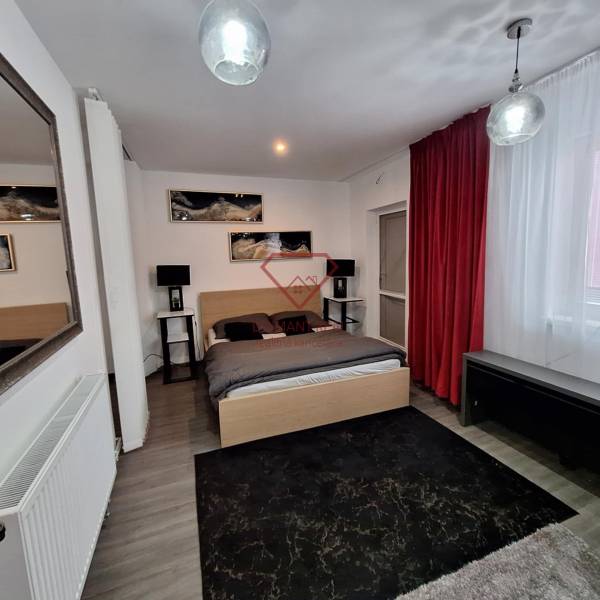 Hálószoba egy családi házban tükörrel, piros függönyökkel és faldekorációkkal.