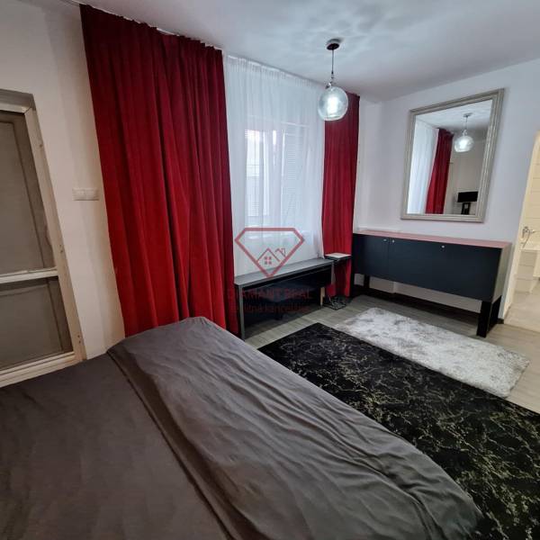 Családi ház belső tere piros függönyökkel, tükörrel és sötét szőnyeggel.