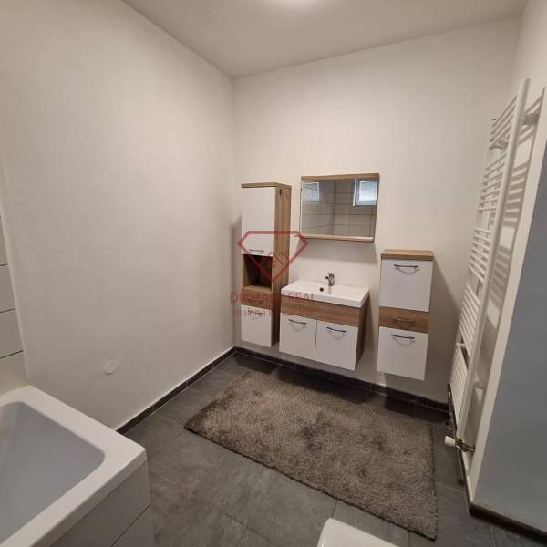 Fürdőszoba családi házban fehér bútorokkal és sötét csempével.