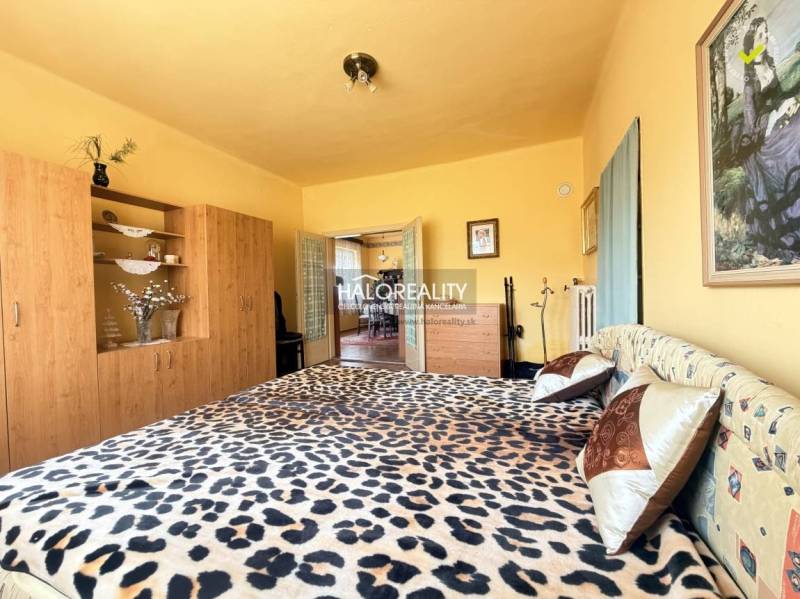 Hálószoba családi házban, leopárdmintás ággyal és fa dekoros szekrénnyel.