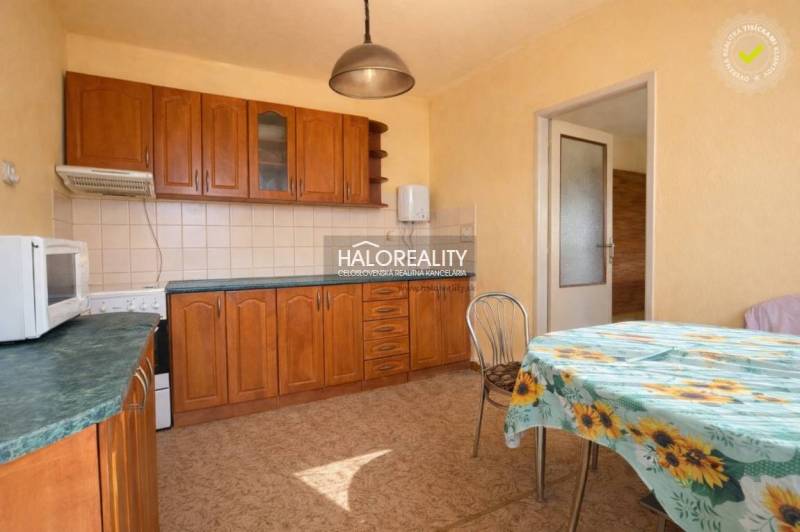 Konyha családi házban beépített szekrényekkel és virágos terítővel ellátott asztallal.