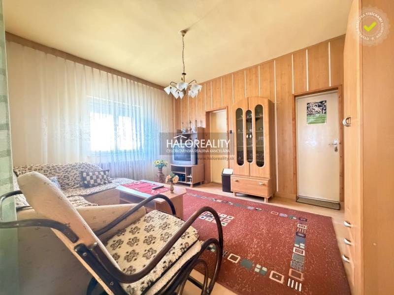 Nappali családi házban ablakkal, fa dekorációjú falakkal és bútorokkal.