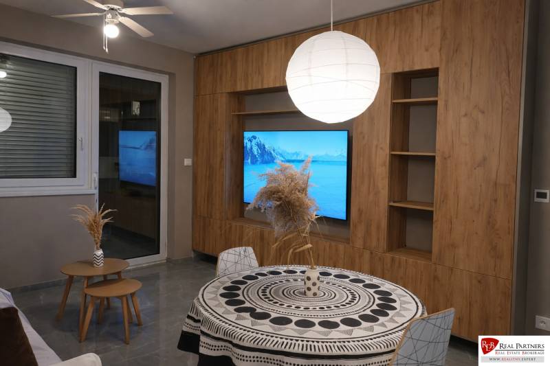 Nappali egy kétszobás lakásban fa dekor padlóval és kerek asztallal.