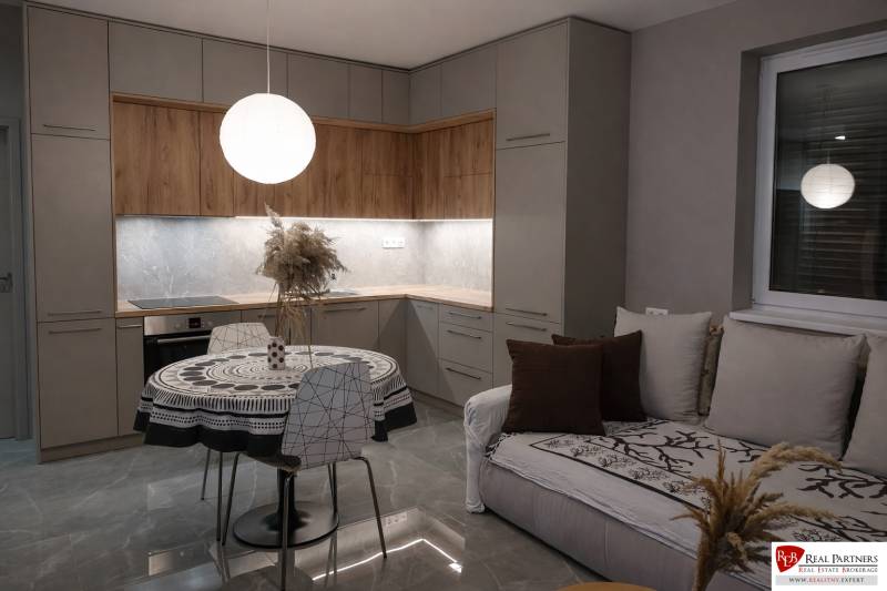 Konyha egy kétszobás lakásban fa dekor padlóval és kerek asztallal.