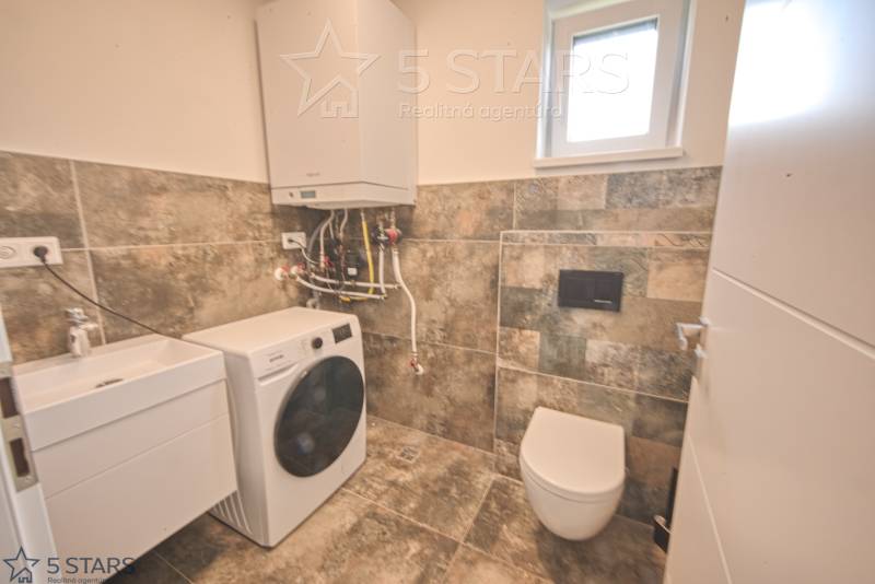 Fürdőszoba családi házban mosdóval, mosógéppel és WC-vel.