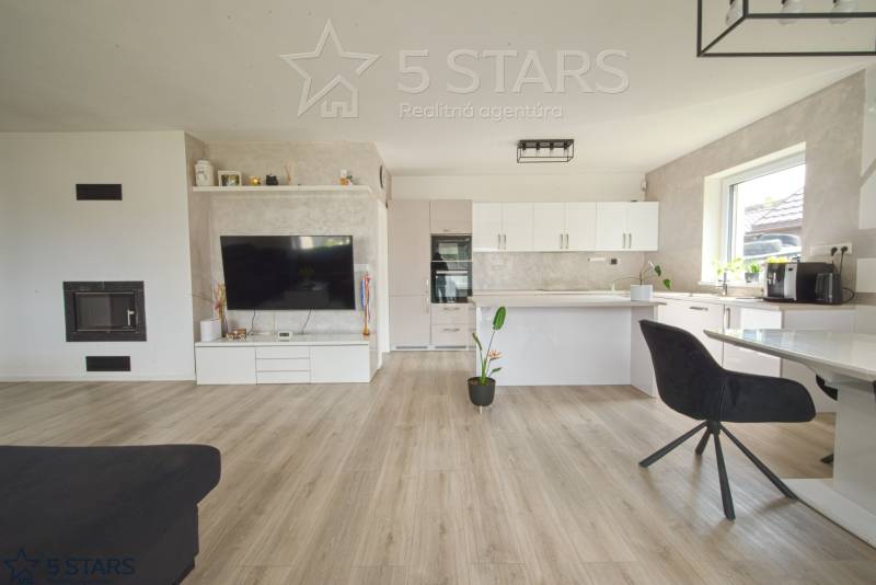 Nappali konyhával a családi házban, világos falak, fa hatású padló.