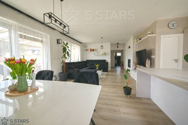 Családi ház belső tere fa dekorációjú padlóval, étkezőasztallal és kanapéval.