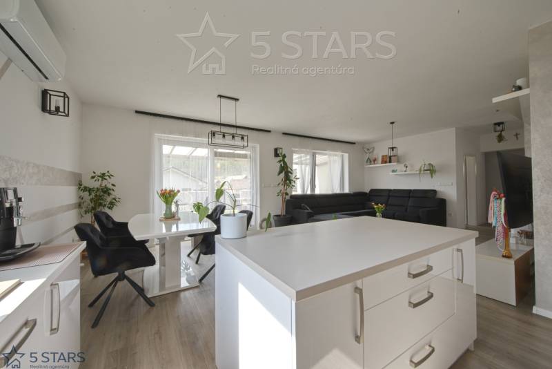 Családi ház belső tere fa dekorációjú padlóval, fehér falakkal és fekete bútorokkal.