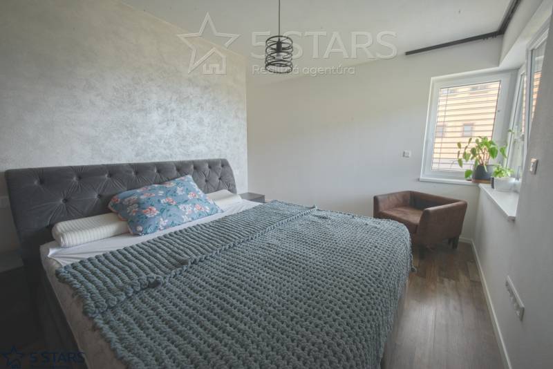 Hálószoba családi házban textil háttámlás ággyal és fa dekorációjú padlóval.