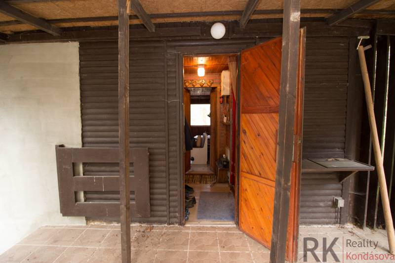 Bejárat a faházzal nyitható ajtóval és verandával az Üdülőtelek területén.