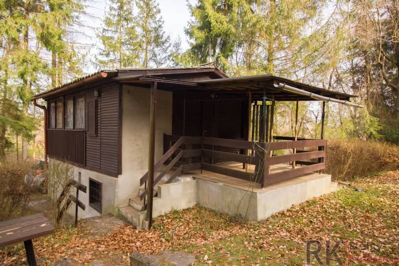 Faház a Holčíkovce-i üdülőterületen, fákkal körülvéve és lehullott levelekkel borítva.