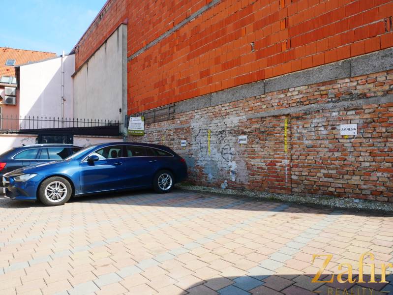 Parkoló a téglaépület mellett a gasztronómiai helyiségekben, Trnava.