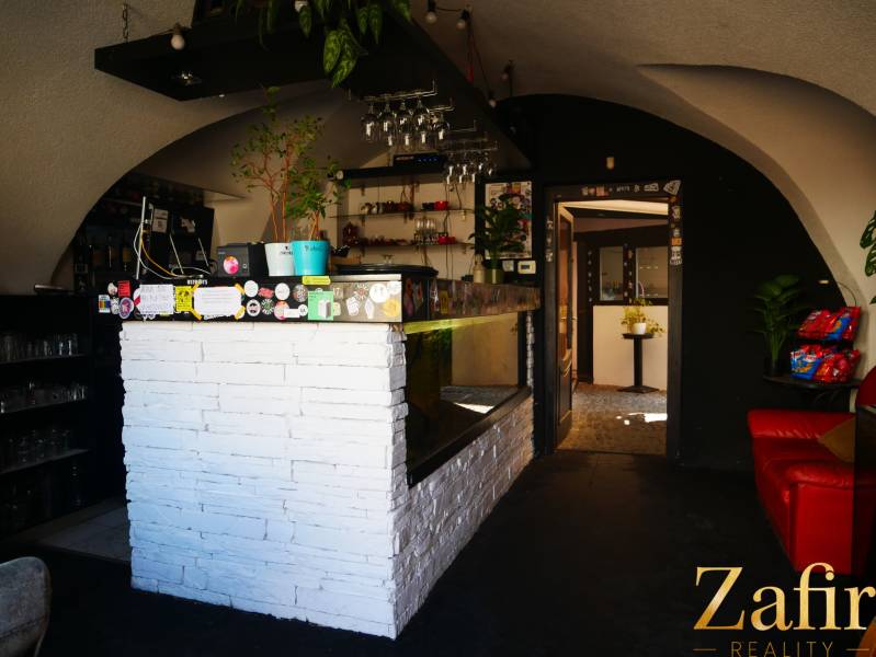 Gasztronómiai tér belső tere fehér bárral, növényekkel és kényelmes ülőhelyekkel.