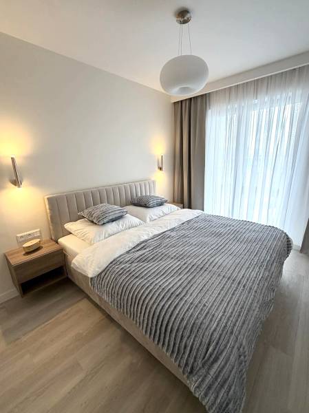 Hálószoba egy kétszobás lakásban fa dekoros padlóval, ággyal és függönyökkel.