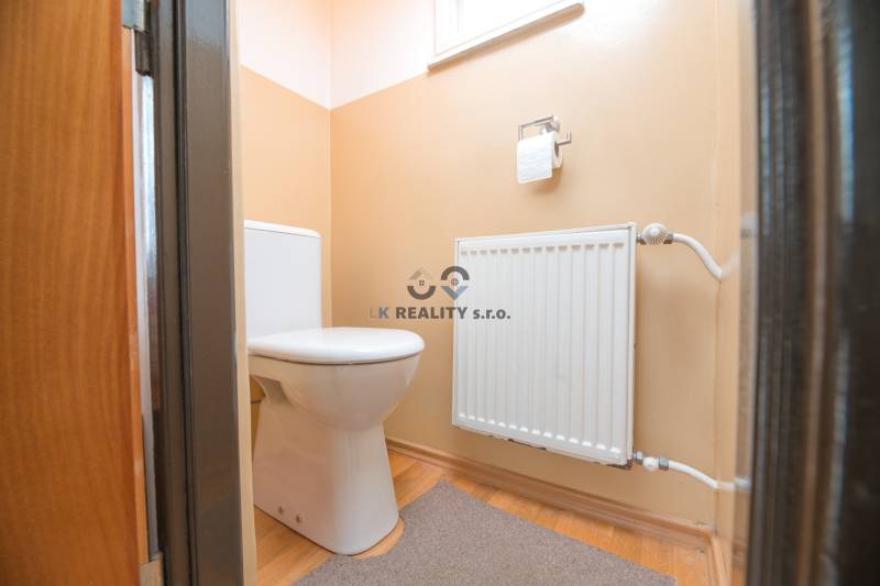 WC egy családi házban radiátorral és fa dekoros padlóval.