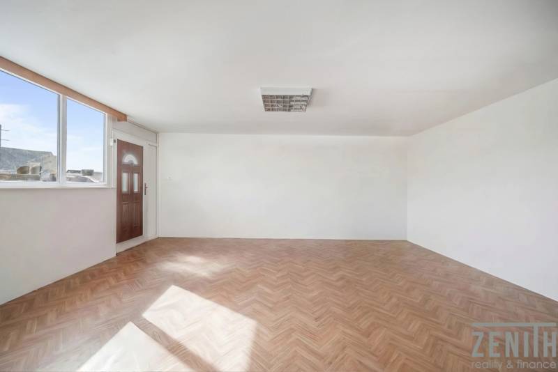 Tágas üzlethelyiség nagy ablakkal és fa dekorációjú padlóval.