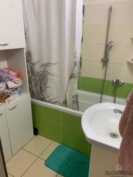 Fürdőszoba káddal és színes csempékkel egy kétszobás lakásban.