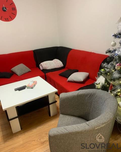 Nappali egy kétszobás lakásban kárpitozott bútorokkal és karácsonyi dekorációkkal.