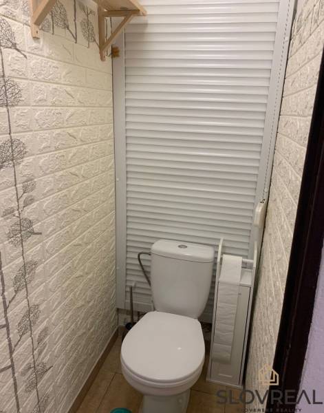 WC tolóajtóval és dekoratív fallal egy kétszobás lakásban.
