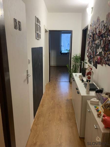 Folyosó fa hatású padlóval, komóddal és dekorációkkal, 2 szobás lakás.