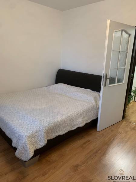 Hálószoba egy kétszobás lakásban fa dekoros padlóval és nagy ággyal.