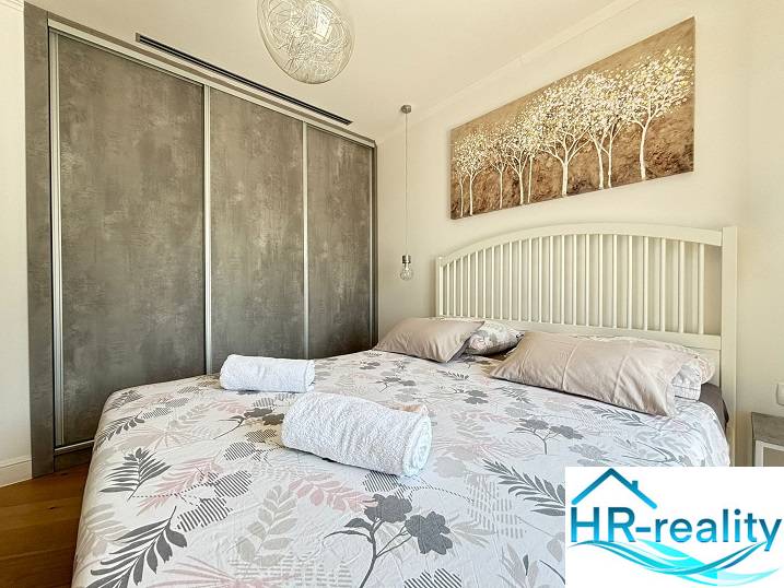 Világos hálószoba a villában nagy ággyal és egy képpel a fejénél.