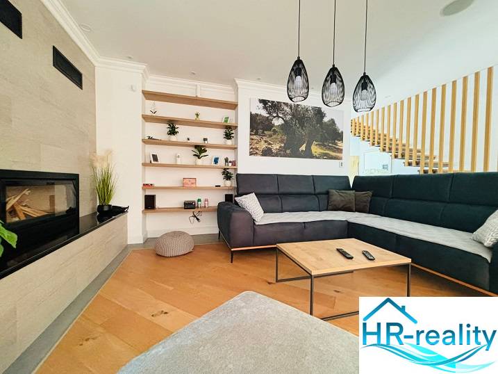 Egy villa belső tere fa dekorációjú padlóval, kényelmes kanapéval és beépített kandallóval.