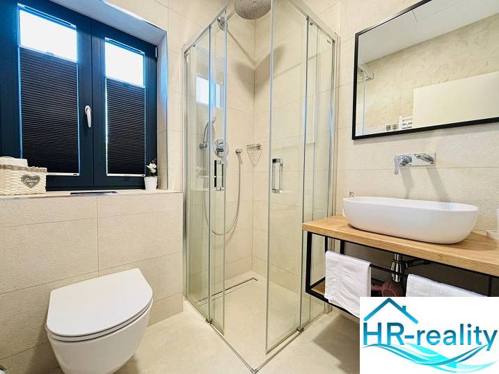 Fürdőszoba a villában zuhanyzóval és mosdóval fa dekorációval.