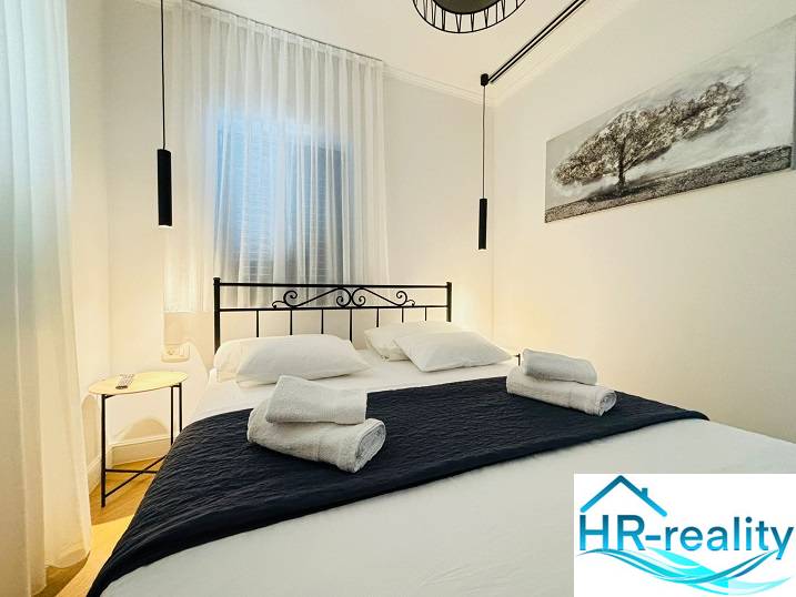 Hangulatos hálószoba egy villában fekete fém ágykerettel és függő lámpákkal.