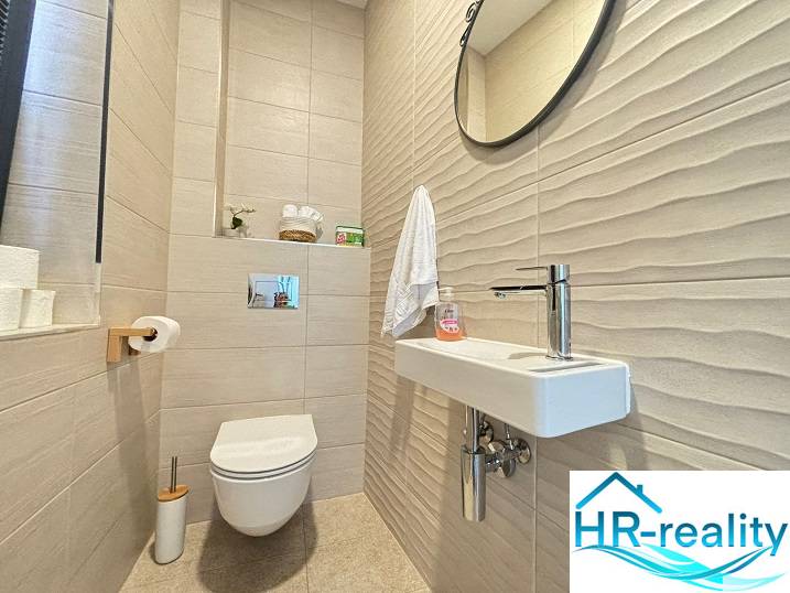 Fürdőszoba a villában csempével, tükörrel és egyszerű mosdóval.