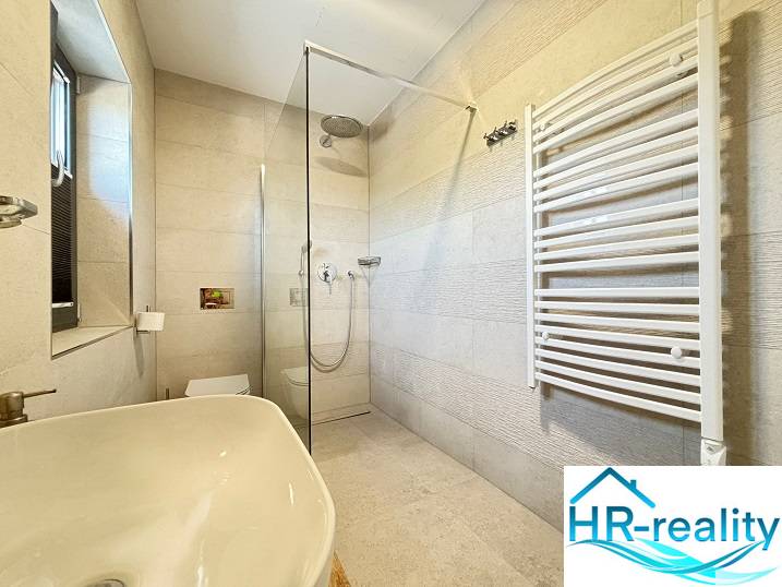 Fürdőszoba a villában zuhanyzóval és fehér mosdóval.