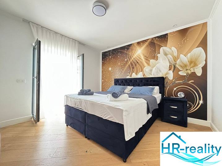 Hálószoba egy villában dekoratív fallal és fa dekorációjú padlóval.