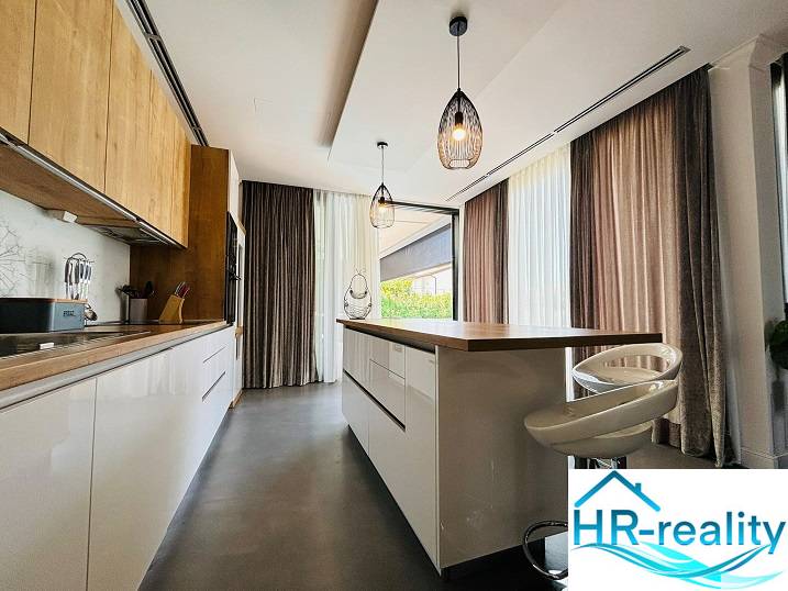 A villa konyhai része stílusos világítással és fa dekorációjú padlóval.