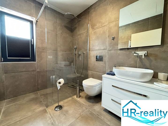 Fürdőszoba a villában nagy zuhanyzóval és függesztett WC-vel.