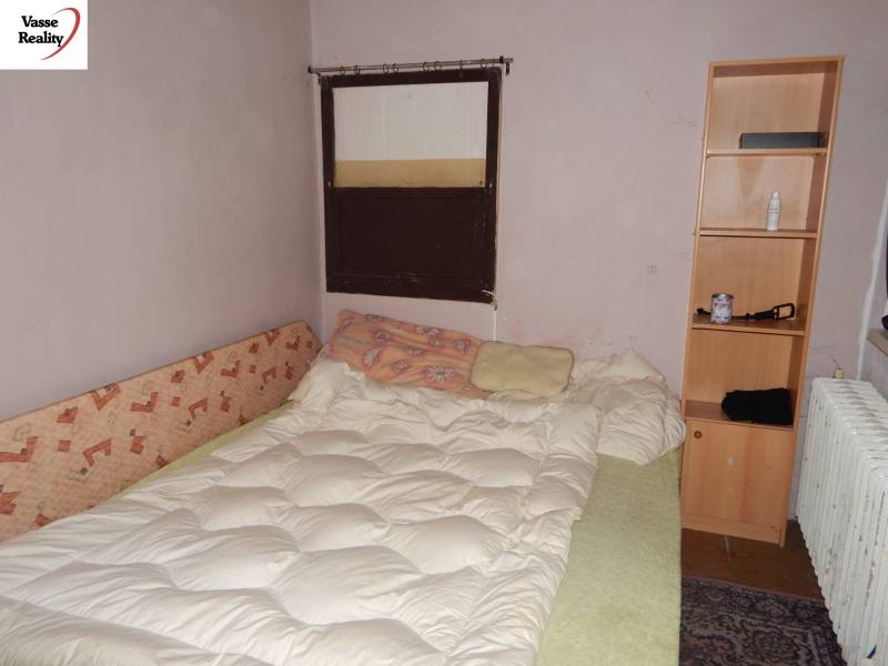 Szoba ággyal, polccal és radiátorral, vendéglátóipari helyiségek felújítására alkalmas.