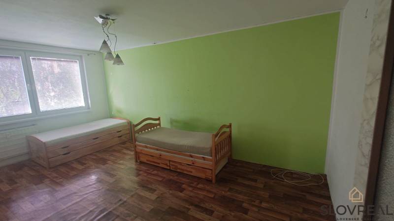 Két hálószobás lakás belső tere két ággyal, fa dekorációjú padlóval, zöld fallal.