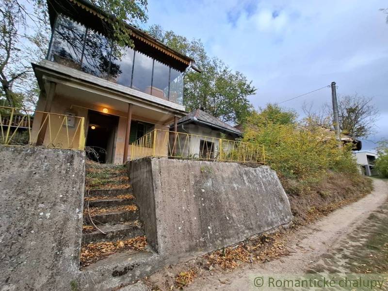 Kőház Kamenínban, zölddel körülvéve, nagy ablakokkal és beton elülső bejárattal.